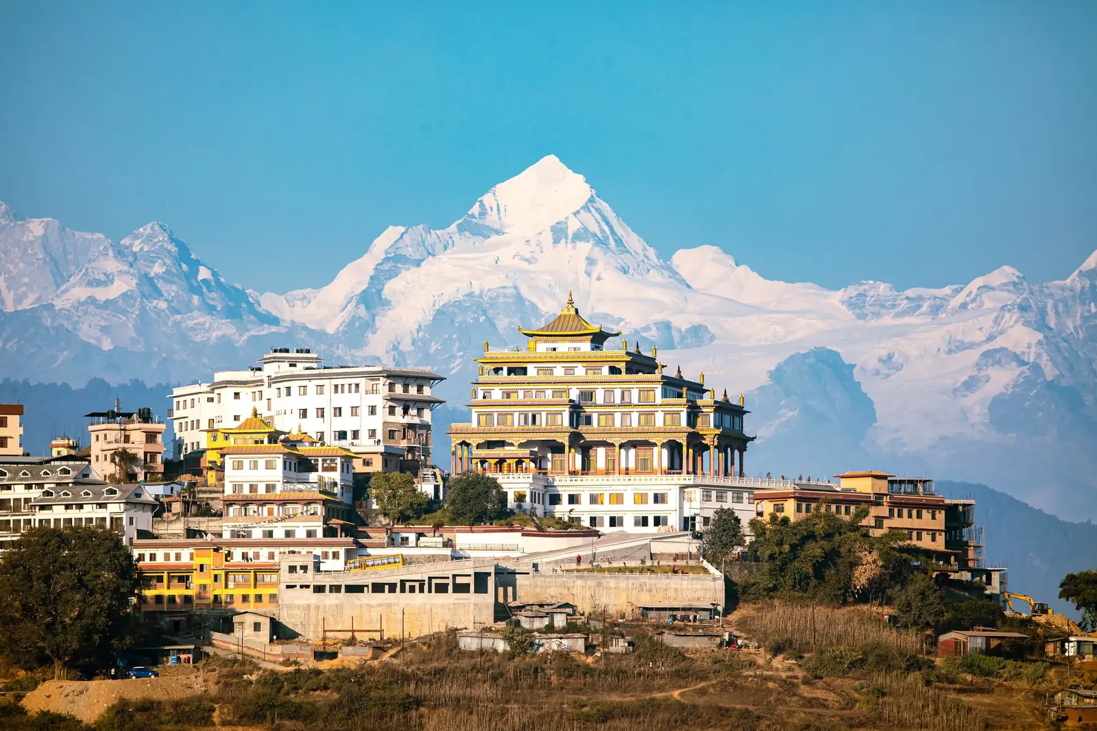 A hilltop Buddhist nunnery at the edge of the Kathmandu valley with the snow peaks of the Jugal Himal behind under a clear blue sky